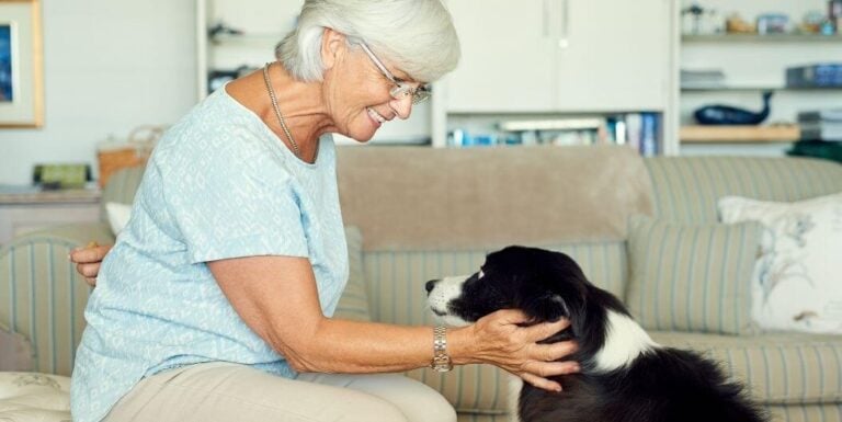 Elderly Woman Smiling While Petting Her Dog At Assisted Living Facility
