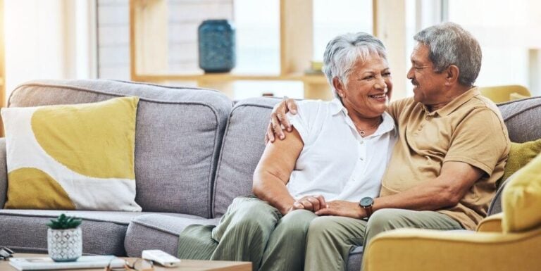 Elderly Couple Relaxing and Smiling Together on Sofa at Assisted Living Facility